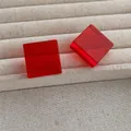 Detail of red acrylic square stud earrings showing transparent geometric cube design - Red