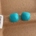 Detailed view of glossy cyan square heart stud earrings on a rustic brown paper background - Square / Blue