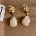 Detail of vintage gold lava texture earrings with cream marble resin teardrop charms - Off White