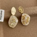Dettaglio di orecchini a pendente con foglia d'oro e scaglie di conchiglia in resina - Bianco Sporco (G205)