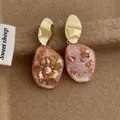 Dettaglio di orecchini in resina rosa con frammenti di conchiglia e foglia d'oro - Rosa (G205)