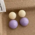 Dettaglio di orecchini retrò in resina a contrasto con doppie sfere crema e lavanda - Bianco/Viola