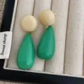 Macro view of cream and green acrylic teardrop earrings in a soft fabric gift box - Green And White (L-18)