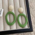 Detail of retro resin hoop earrings with beige studs and green oval pendants on fabric - Green