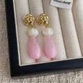 Détail macro de clous de rose dorés avec boucles d'oreilles en résine marbrée rose - Rose