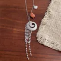 Detail of seashell pendants and white bead tassels on a titanium steel necklace - Spiral Style