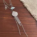 Detailed shot of starfish and shell charms with pearl tassels on a silver-tone long necklace - Shell Style