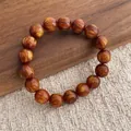 Macro detail of reddish-brown beaded bracelet with golden silk texture on wooden background - Small Style