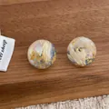 Detailed macro view of clear resin ball earrings with dried flowers and gold foil accents - Round (R181) / Blue Series