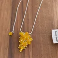 Detail showing yellow grape cluster beads on a silver snake chain over wood - Yellow