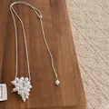 Close-up of pearl cluster pendant on silver snake chain over a rustic wooden background - Pearl White