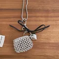Detail of silver woven mini bag pendant with heart charm and black bow on wooden surface - Black Bow Style / Silver