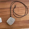 Macro shot of silver woven heart pendant on black cord over dark wooden background - Black Rope Style / Silver