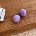 Detailed close-up of glossy purple semi-sphere stud earrings on a wood background - Purple