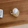Dettaglio anello artistico con pietra ovale bianca e fili metallici dorati intrecciati - Ovale / Ovale Oro Contrasto