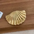 Détail d'une broche coquillage plaquée or 18 carats avec texture rayonnante sur bois - Style Coquillage / Doré