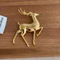 Close-up of a polished gold elk brooch on a minimalist rustic wooden background - Gold