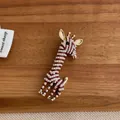 Detailed view of giraffe brooch with white pearls and red enamel on dark wood - Red Giraffe Style (M-199)