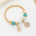 Close-up of golden spring bracelet with starfish and pavé heart charms on lace background - Gold Sky Blue Heart Starfish Style (10)