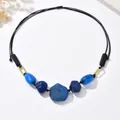 Macro detail of bohemian necklace featuring blue marble beads and black woven cord - Blue