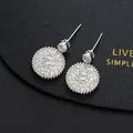 Macro shot of silver starburst earrings with white zircon on black leather background - Silver Sunburst Star Round Dangle Style(I)