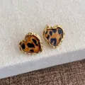 Dettaglio di orecchini a cuore con stampa leopardata e bordo dorato a treccia - Leopardo Cuore
