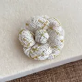 Macro shot of white tweed camellia brooch with gold metallic threads and petal texture - White