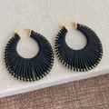 Dettaglio di orecchini neri a ventaglio intrecciati con piccole perline dorate - Base Oro Nero