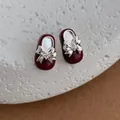 Macro-opname van rode emaille Mary Jane schoen oorbellen met zilveren strik en kristal - Rood