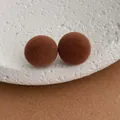 Close-up of brown flocked sphere earrings on textured white and craft paper background - Brown