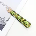 Detalle de un llavero de muñeca bordado bohemio con motivo floral amarillo y cierre de metal oro - Floral geométrico verde amarillento (Patrón geométrico-04)