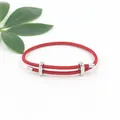 Detailopname van rode gevlochten armband met verstelbare zilveren metalen gespen - Rood