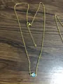 Detail of gold-plated evil eye necklace with lobster clasp on wood surface - Green Eye Gold