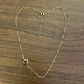 Elegant gold-tone stainless steel Star of David pendant necklace on a dark wood background - Gold