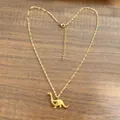 Golden dinosaur pendant necklace with hollow heart detail on wooden background - Gold
