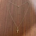 Dettaglio del ciondolo croce Ankh dorata con catena sottile su fondo in legno scuro - Collana (Con Catena) / Oro Piccolo