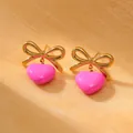Detail of gold bow earrings with a glossy pink heart pendant on a textured background - 18K Gold / Hot Pink