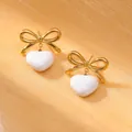 Elegant gold bow earrings with white heart pendants on a textured silk backdrop - 18K Gold / White