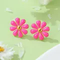 Gros plan de boucles d'oreilles marguerites roses avec centres dorés sur fond vert doux - Boucles d'Oreilles Fleurs Roses