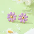 Vue macro de boucles d'oreilles marguerites mauves au centre doré sur fond vert doux - Boucles d'oreilles fleurs violettes