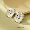 Detail van zilveren vintage rechthoekige oorbellen met reliëftextuur en afmetingen - Vierkant Staalkleur