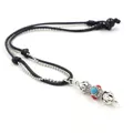 Close-up of vintage vajra pendant with turquoise bead and braided cord necklace detail - Vajra Style