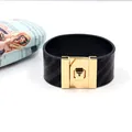 Detailopname van brede zwarte lederen armband met een goudkleurige metalen draaisluiting - Zwart
