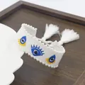 White woven evil eye bracelet with embroidered patterns, pearls and adjustable tassel cord - White