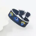 Detailed close-up of handmade evil eye embroidered bracelet with beads and tassels - Black