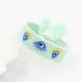 Detail van mintgroene geweven armband met boze oog borduursel en witte parelranden - Lichtgroen