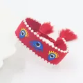 Detail van rode geweven armband met geborduurde boze ogen en witte imitatieparelranden - Rood