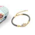 Gevlochten leren armband met Hamsa-hand en boze oog op een decoratieve doos - Hamsa Hand Stijl / Grijs