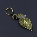 Retro bronze metal leaf keychain with brown leather strap and engraved tag on black surface - Large Leaf Style (HM2008-20) / Bronze