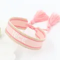 Detail van roze geborduurde armband met NICE-tekst en decoratieve handgemaakte kwastjes - Roze NICE-4 Stijl